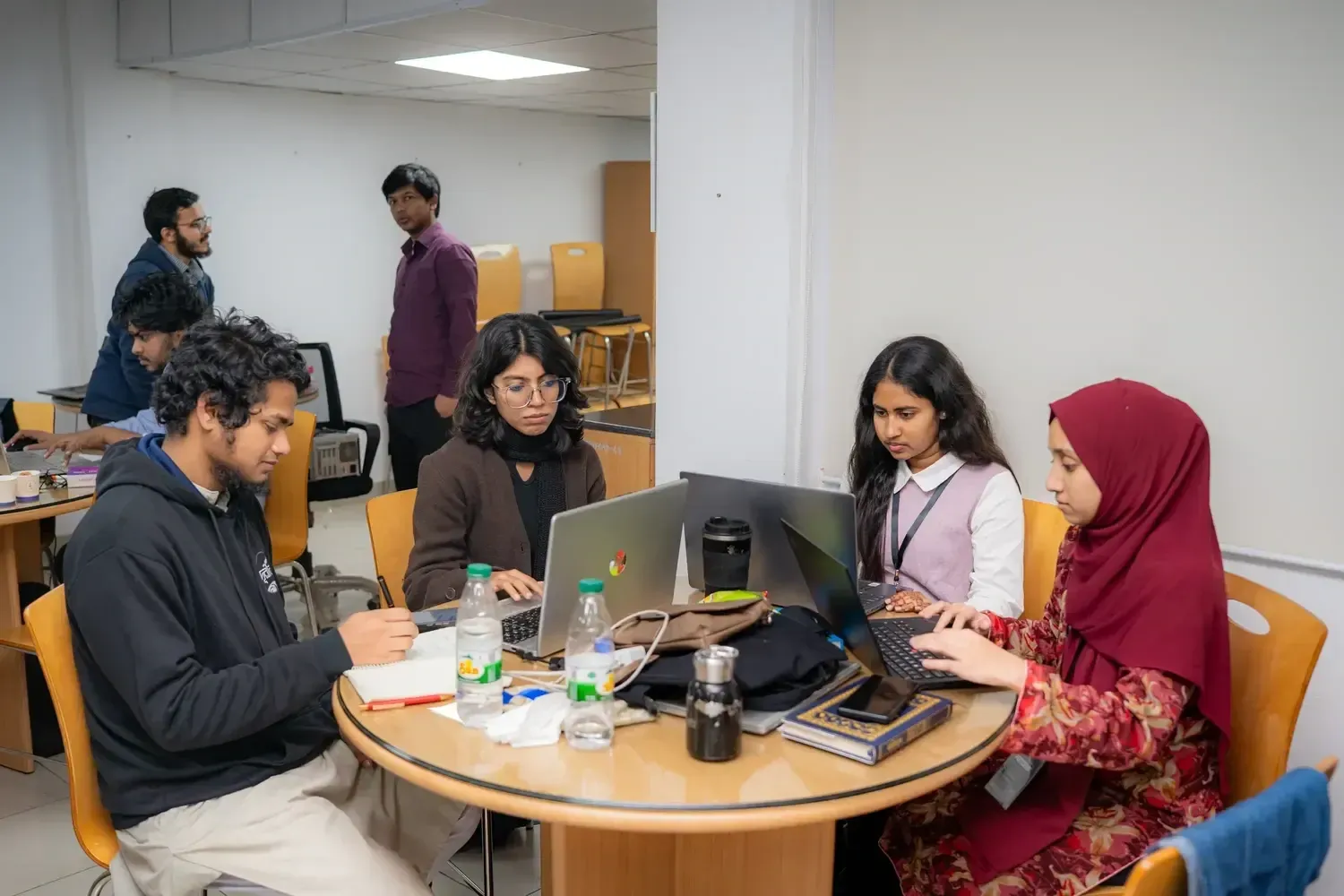 Four workshop participants working individually on laptops and notes around a table.