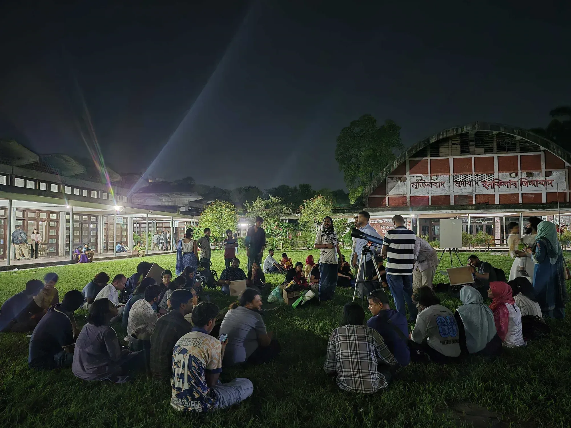 People seated in a circle around a telescope during a Durbin public evening
