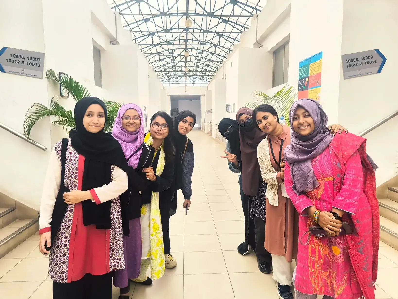 Seven Durbin Workshop 2 participants standing together in a bright IUB corridor.