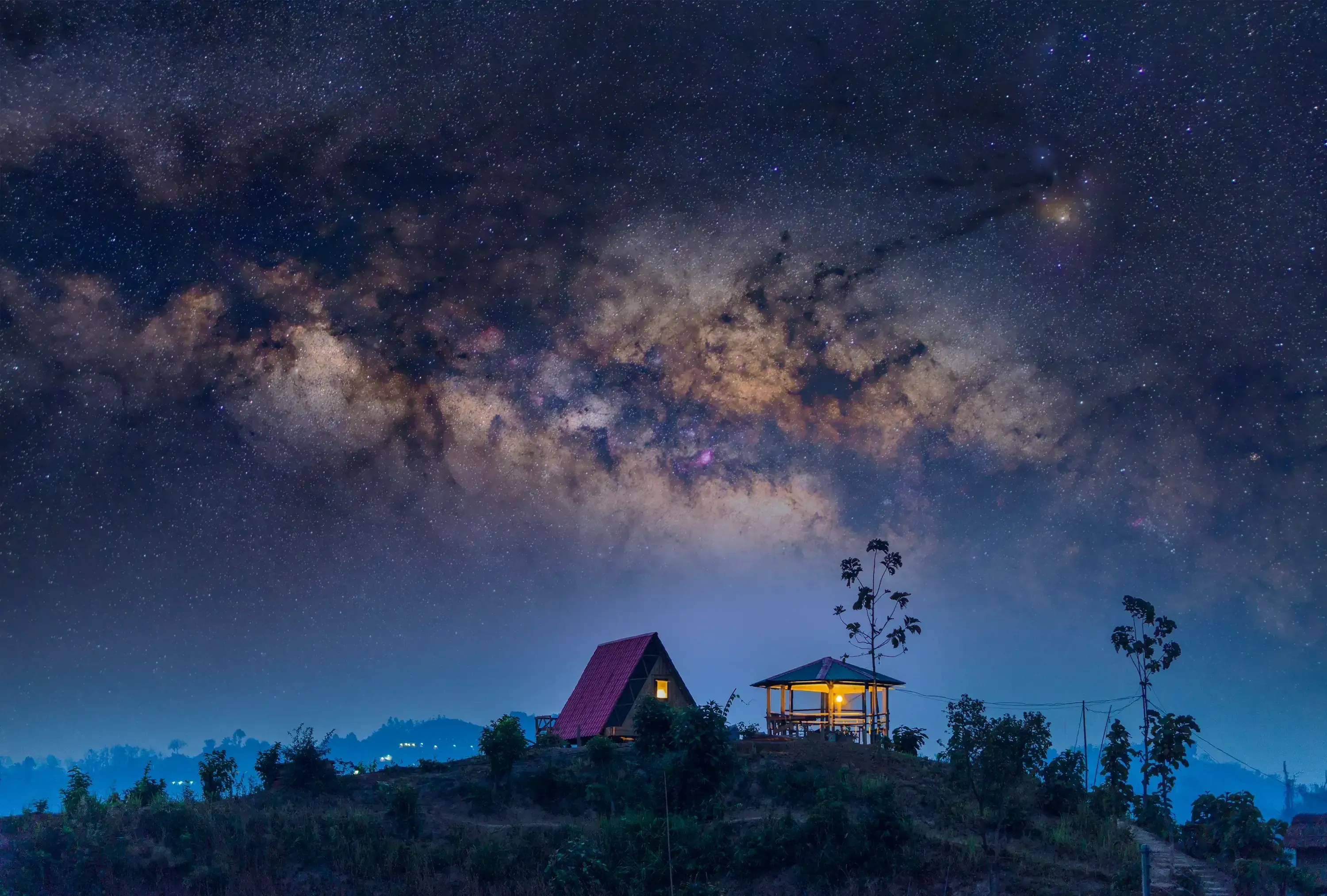 The Milky Way core arching over a hilltop cabin in Bandarban