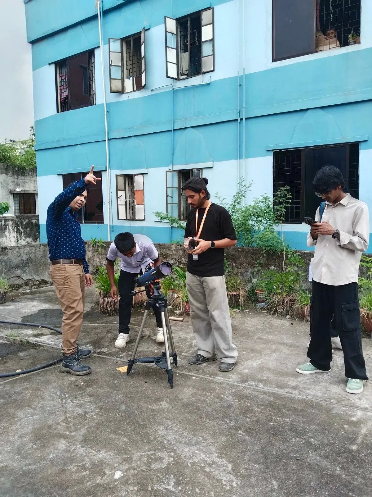 Students and volunteers gather around the Celestron 200AZ telescope on the school rooftop.
