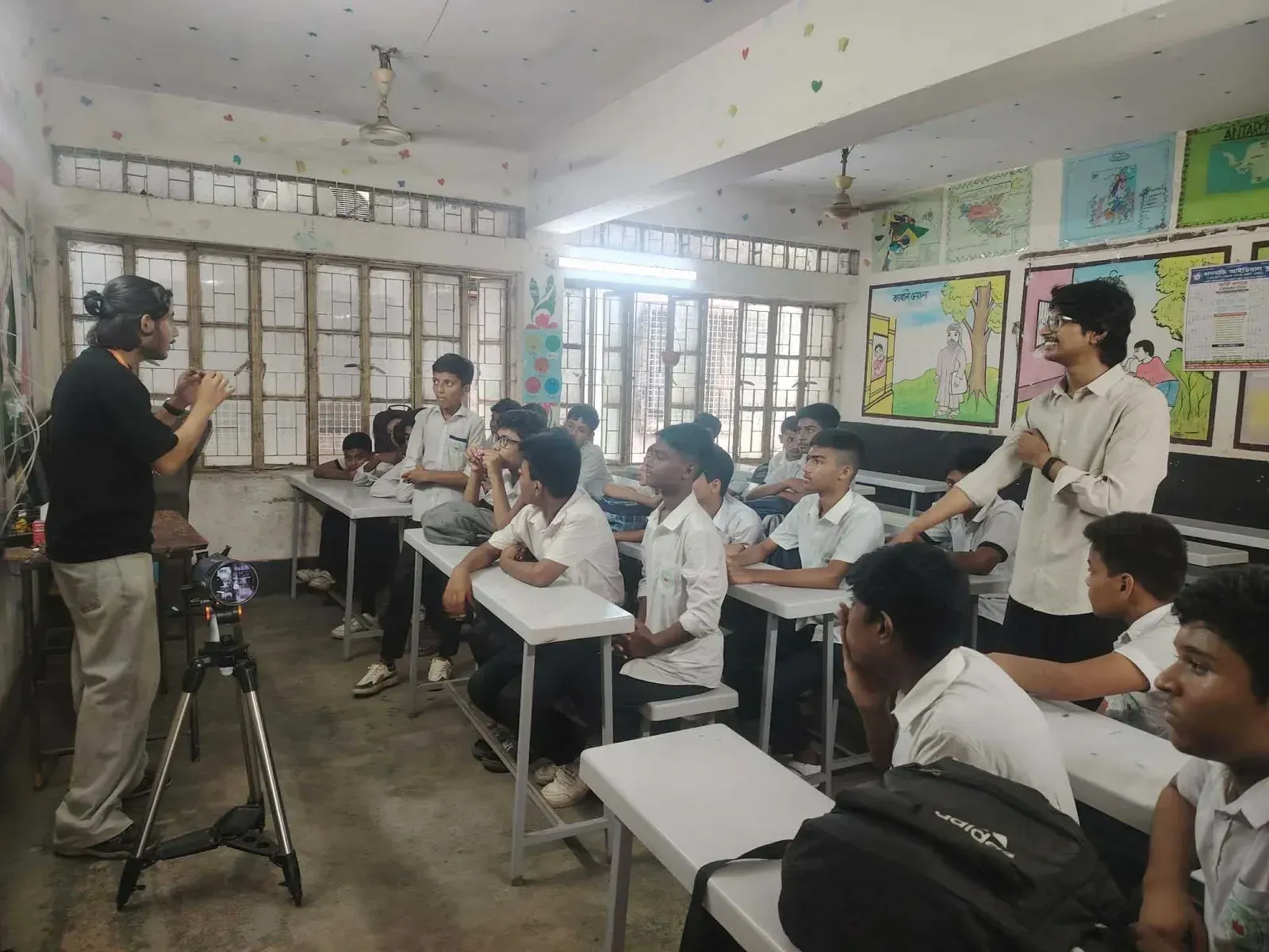 A volunteer explains how a telescope works to a classroom of seated students.