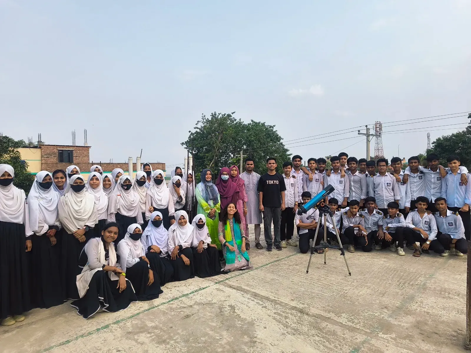 Durbin volunteers and the students of Nagarbari Maritime School and College gathered around a telescope for a group photo.