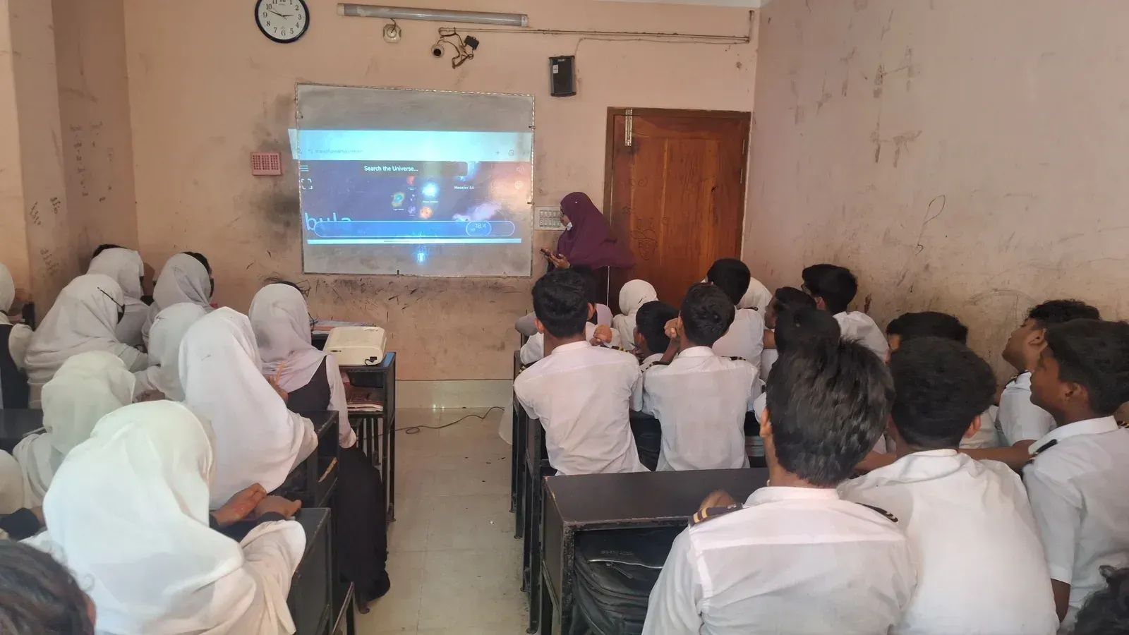 A volunteer running the Scale of the Universe website on a projector for a classroom of students.