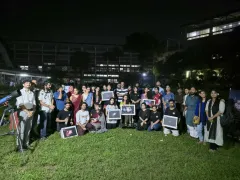 Participants and Durbin volunteers gathered on the TSC lawn at night, several holding framed astrophotographs, with a telescope at the left of the frame.