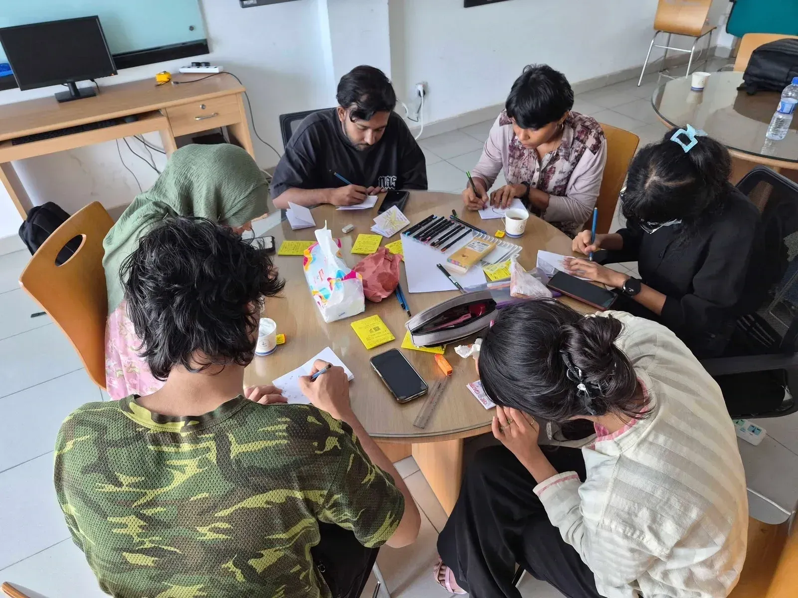 Participants working on their zines around a table with markers and sticky notes.